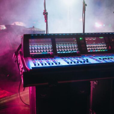 A vibrant shot of a professional audio mixer on a stage under colorful lights, ready for a live performance.