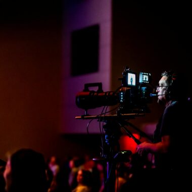 A videographer operates a camera during a live event, capturing the action professionally.