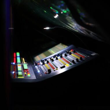 Close-up of a digital audio mixer at a music concert with vibrant lights.