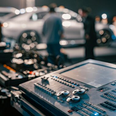 Close-up of a sound mixer at a lively indoor event with blurred people in the background.