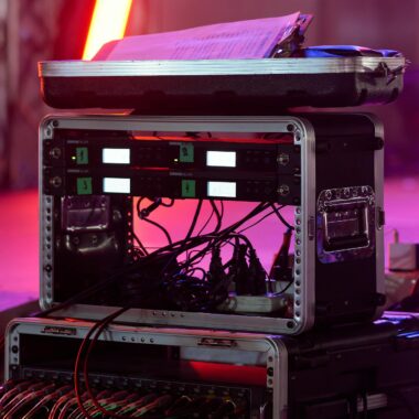 Close-up of audio equipment with colorful stage lights at a live event, showcasing professional sound gear.